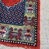Vintage hand-knotted wool rug with polychrome decoration on a red, blue, green background 150 x 63 cm
