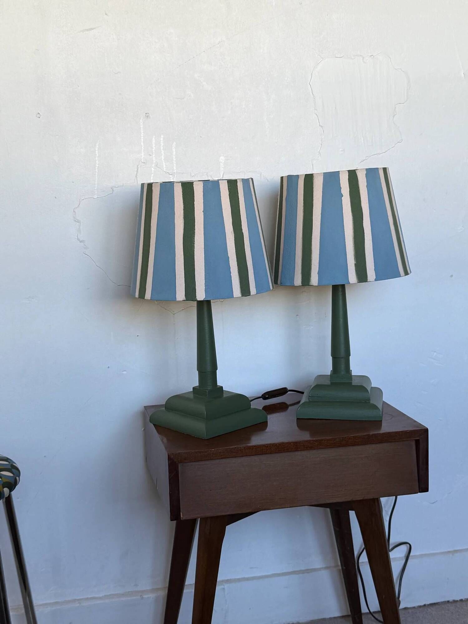Pair of vintage wooden lamps with their striped beige, blue, and green shades.