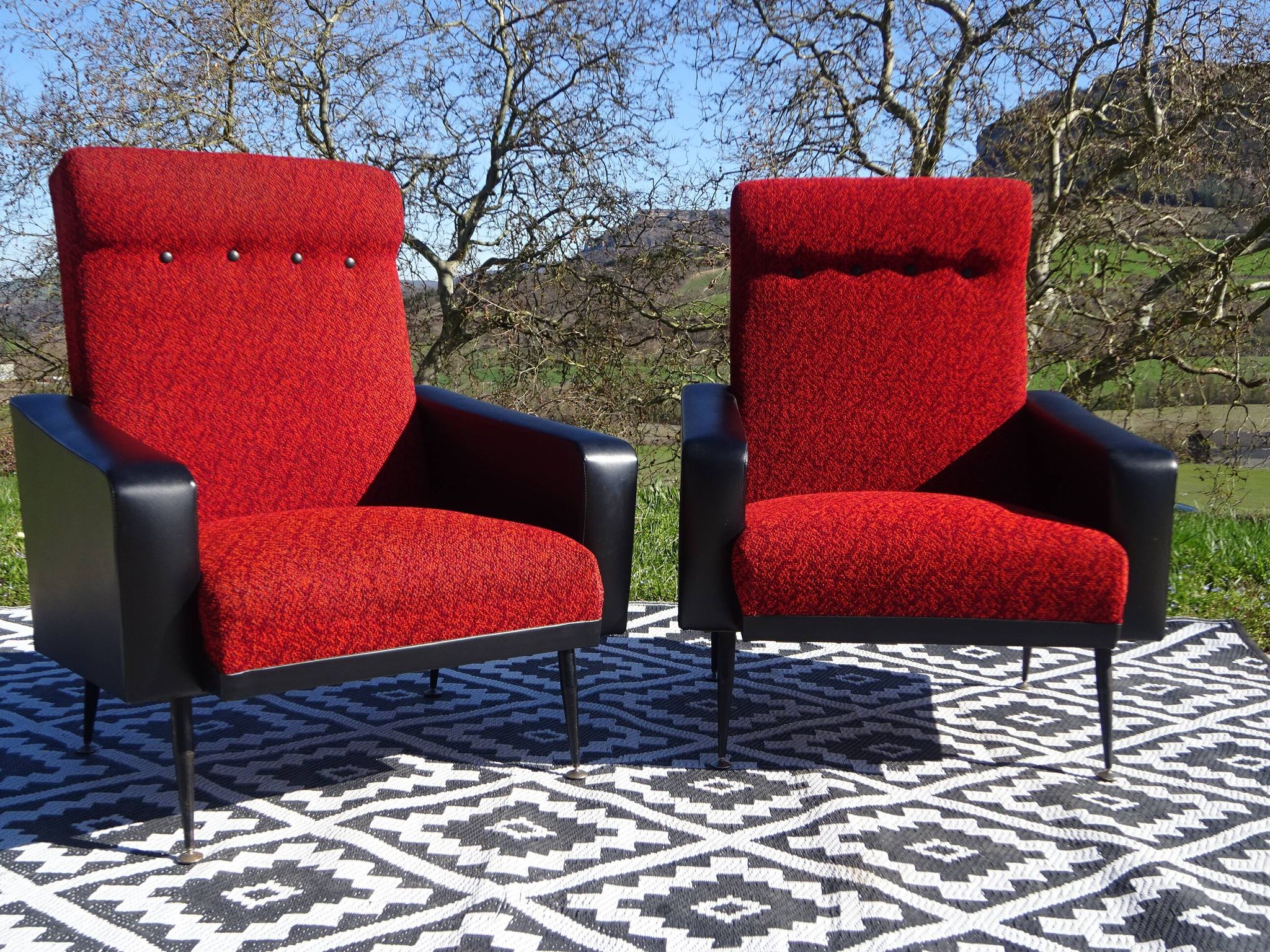 Pair of vintage armchairs in black faux leather and red fabric.