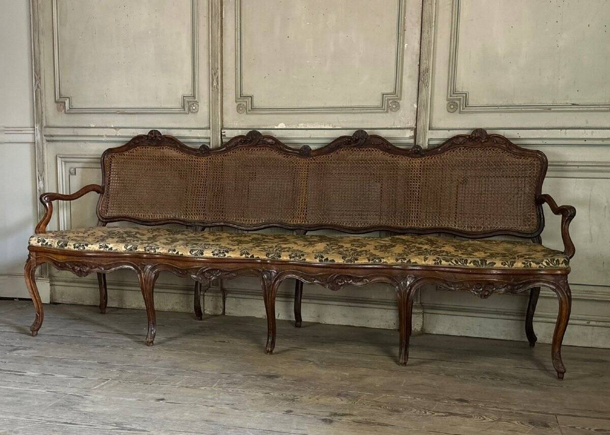 Grande banquette Louis XV en bois naturel mouluré et sculpté, France XVIIIème siècle