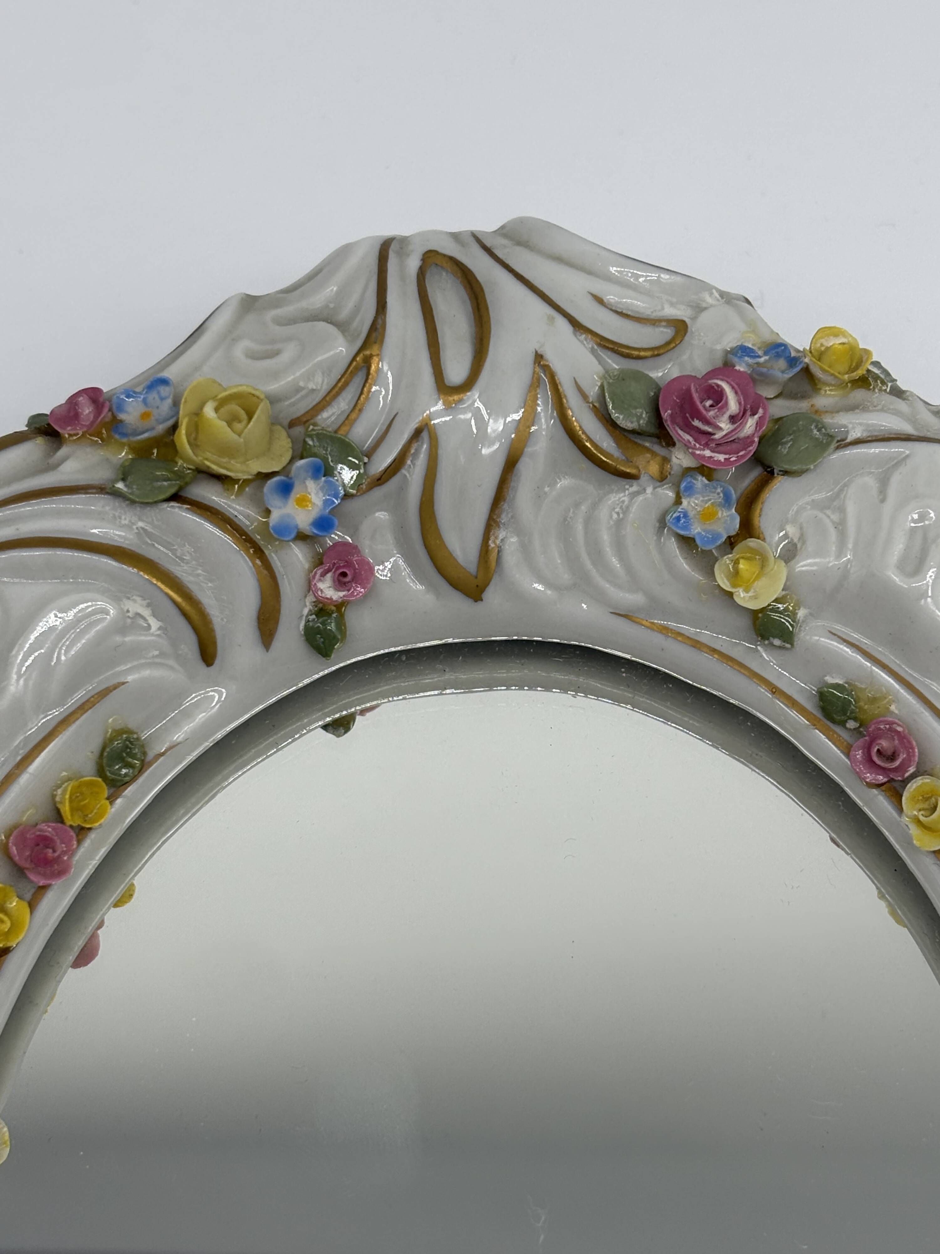 Antique porcelain mirror from Dresden with relief flowers and rococo decoration.