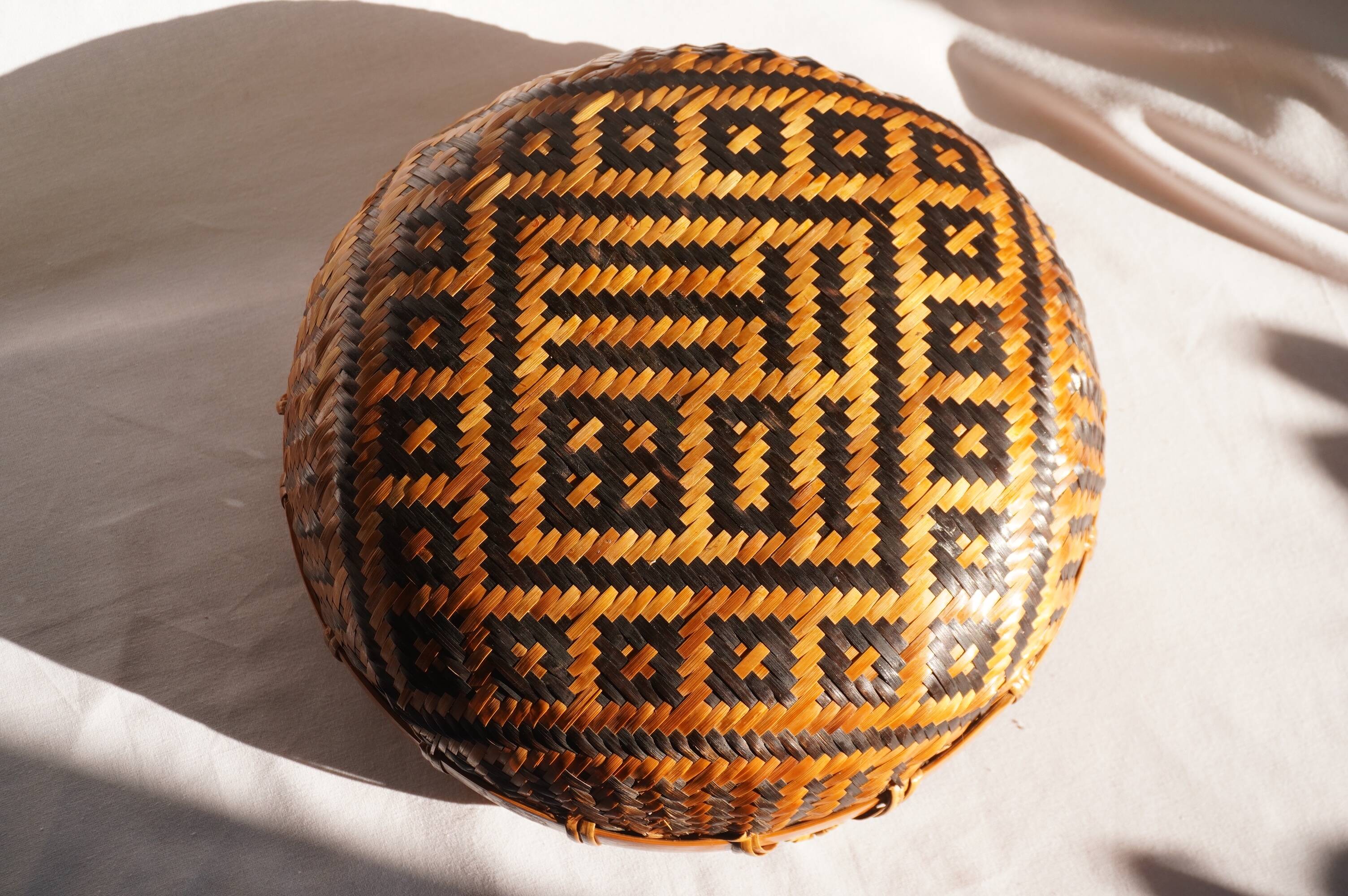 Woven patterned basket, made of straw and bamboo.