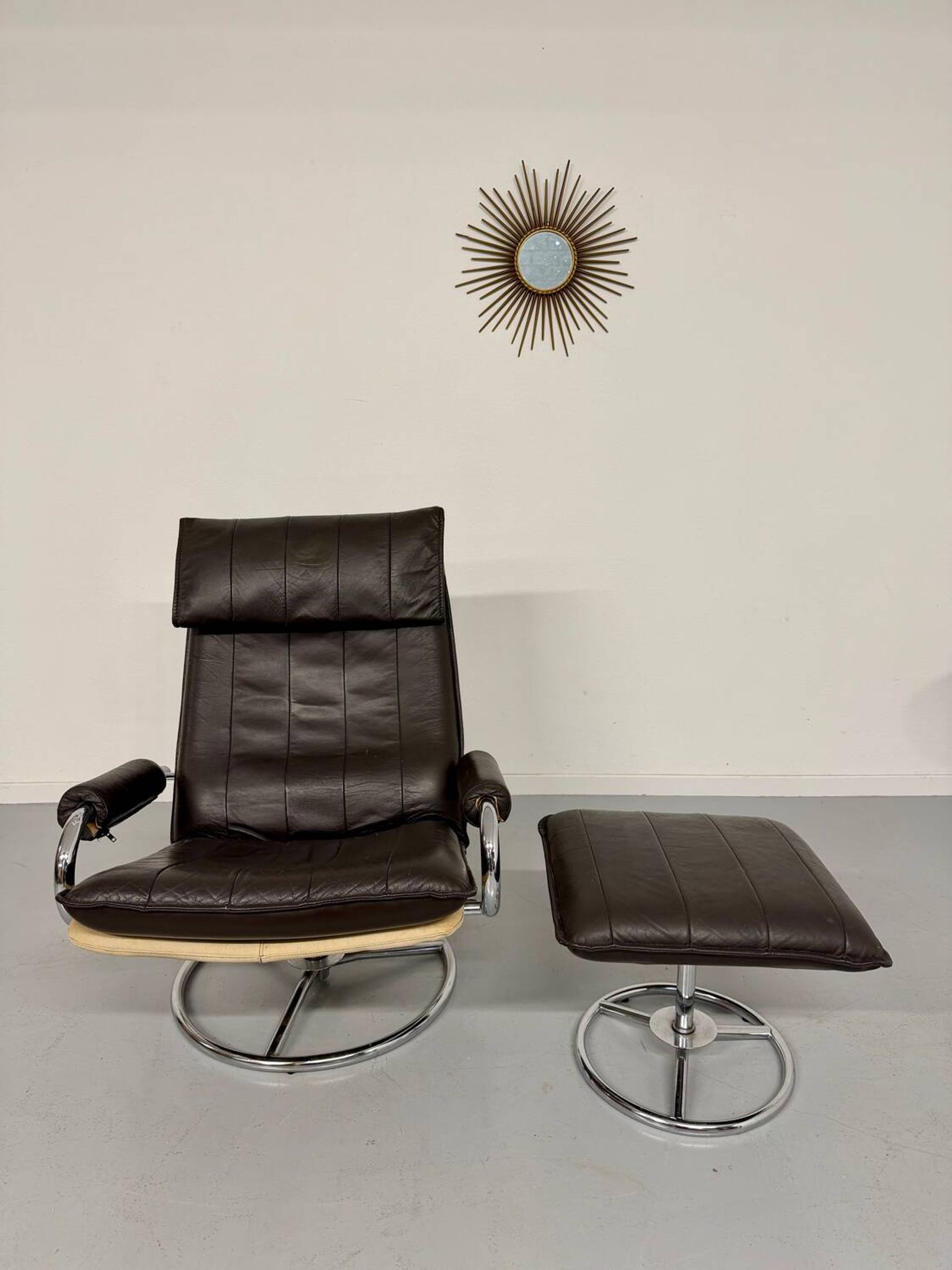 Vintage leather reclining armchair and its 1970s designer ottoman.