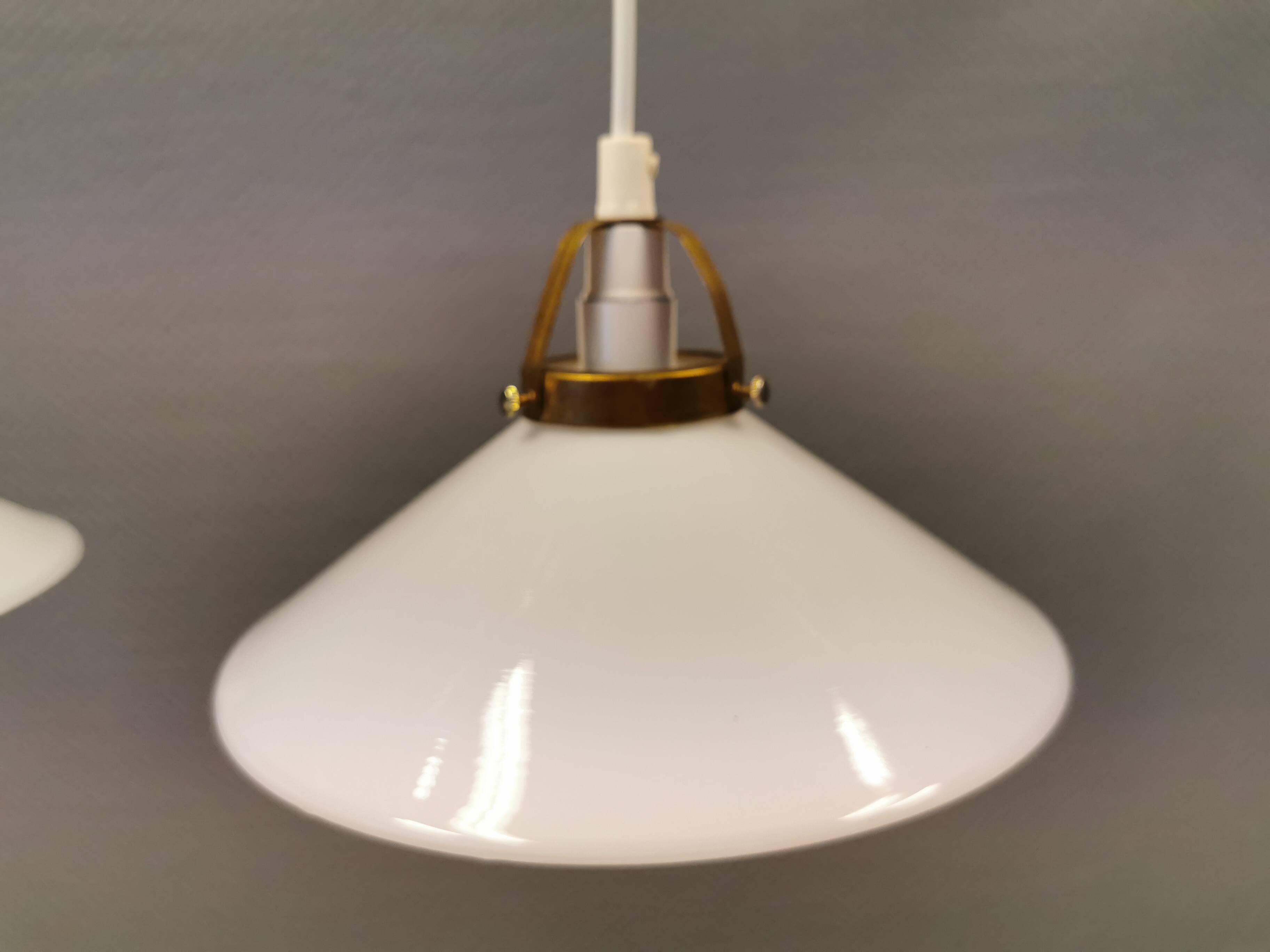 A set of hanging lamps in milky white opal glass with brass top.