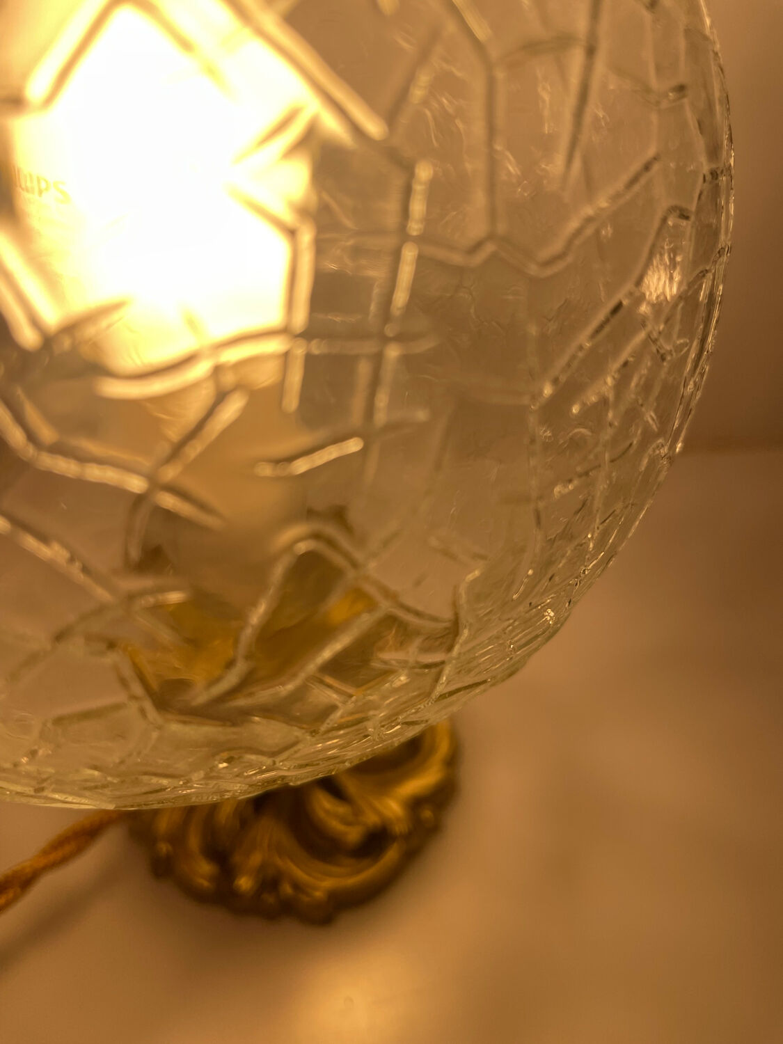 Small handcrafted globe lamp with a cracked finish and a golden brass base.