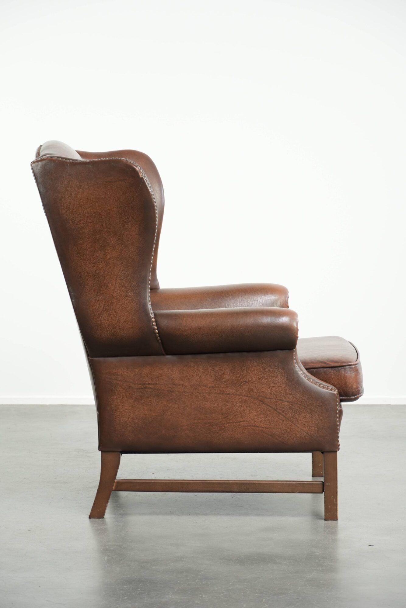 Cowhide wingback armchair in English style finished with decorative nails