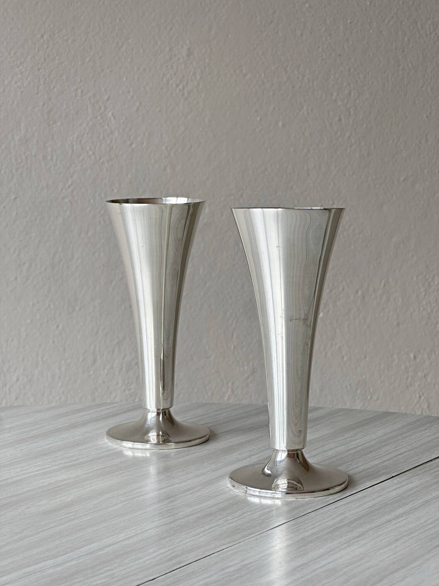 Two silver-coloured lightweight metal flower vases.