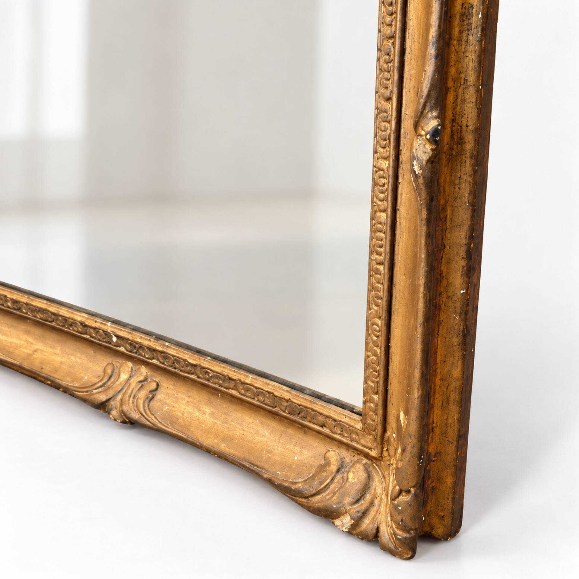 Antique mirror with a gilded frame and foliage decoration.