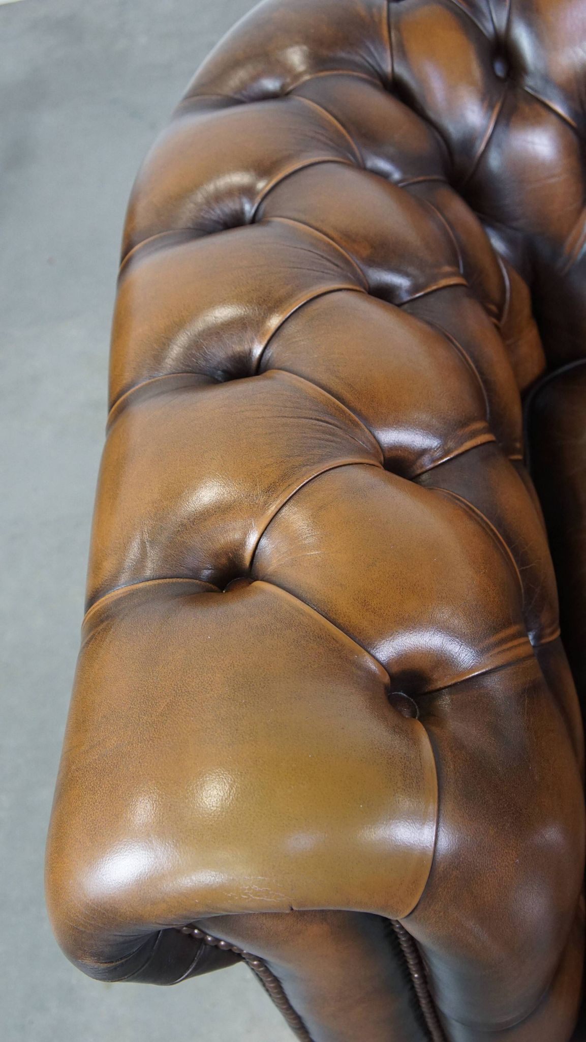 A well-maintained cowhide leather English Chesterfield armchair