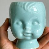 Turquoise plant pot in the shape of a vintage doll's head.