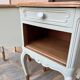 Renovated bedside tables in laurel green and light wood.