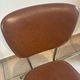 Two brown faux leather chairs.