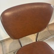 Two brown faux leather chairs.