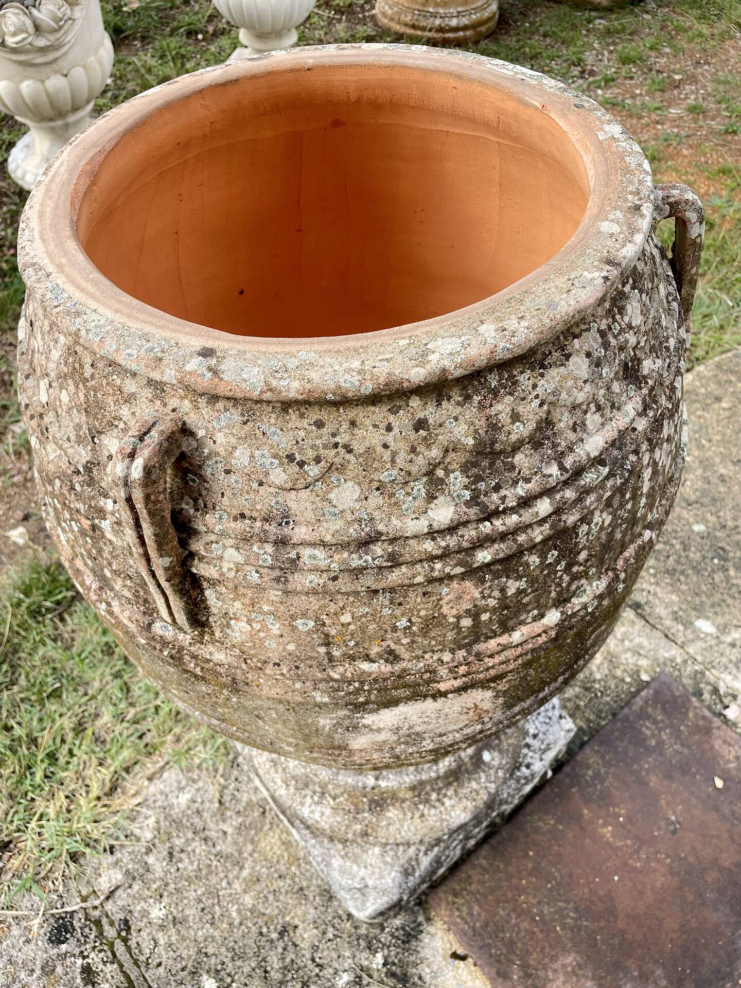 Large Cretan jar in terracotta with three handles on a stone base.