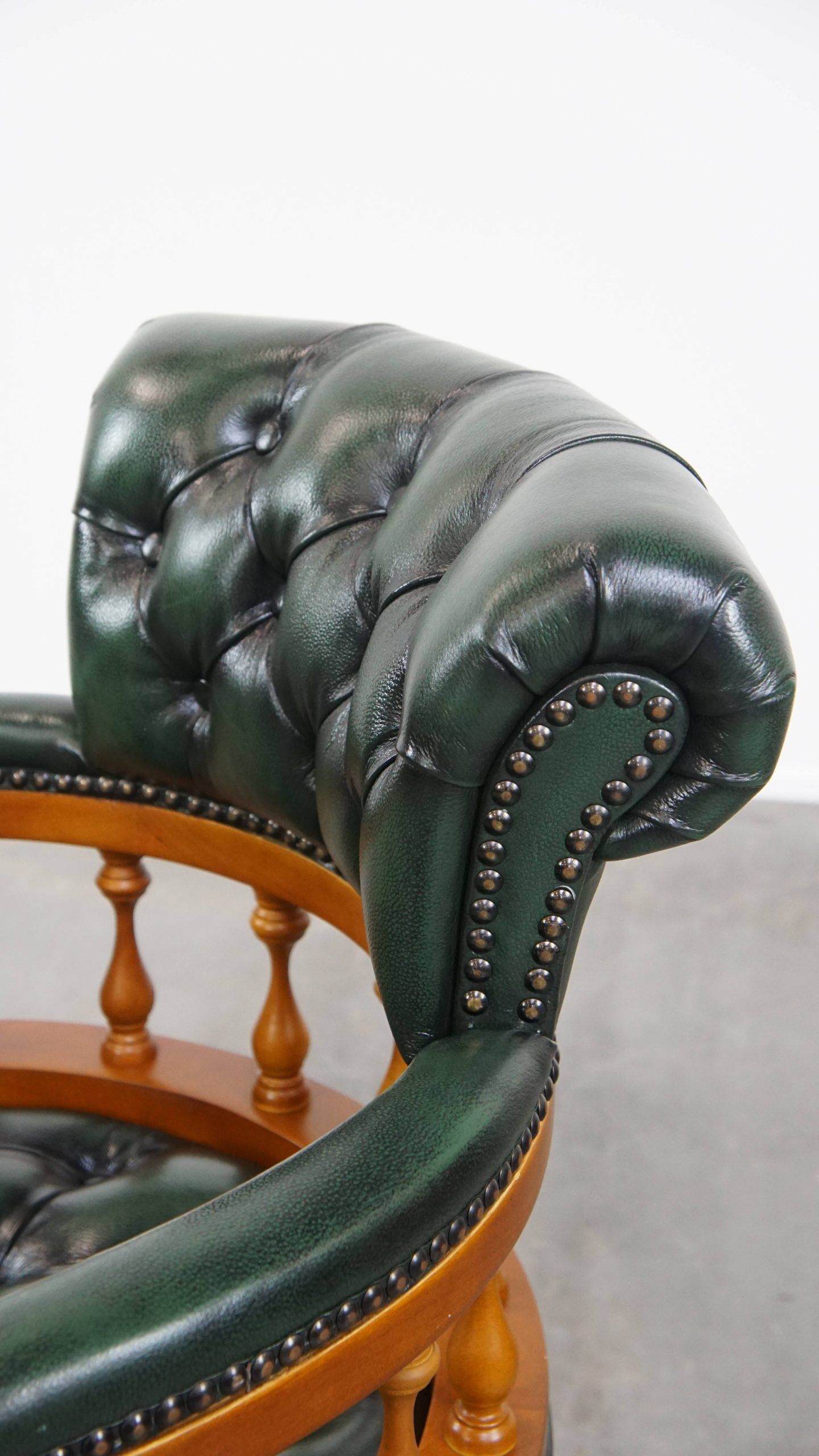 Classic green leather Chesterfield office chair on wheels.