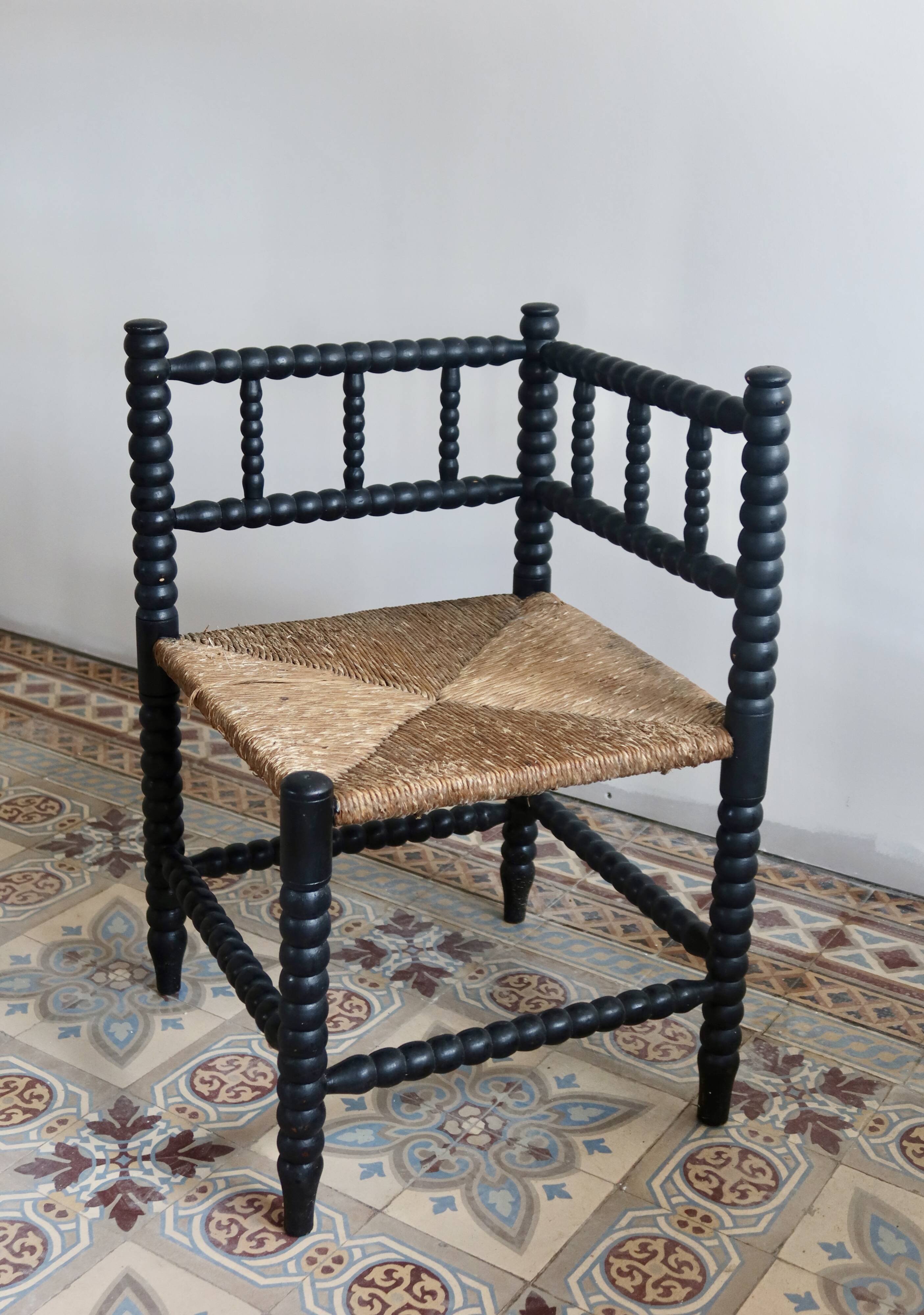 Antique black turned wood corner chair with a straw seat.