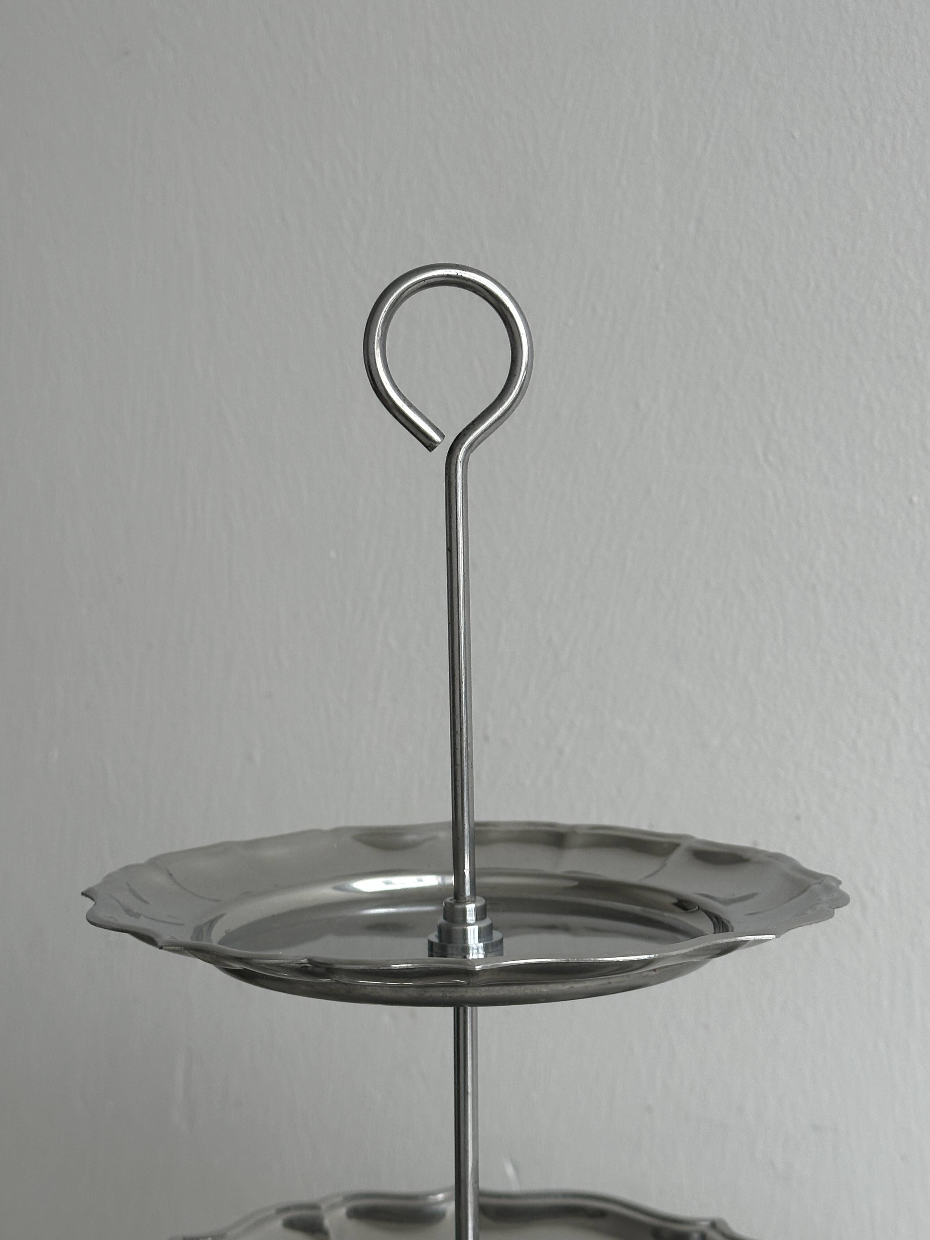 Three-tiered serving trolley in shiny stainless steel.