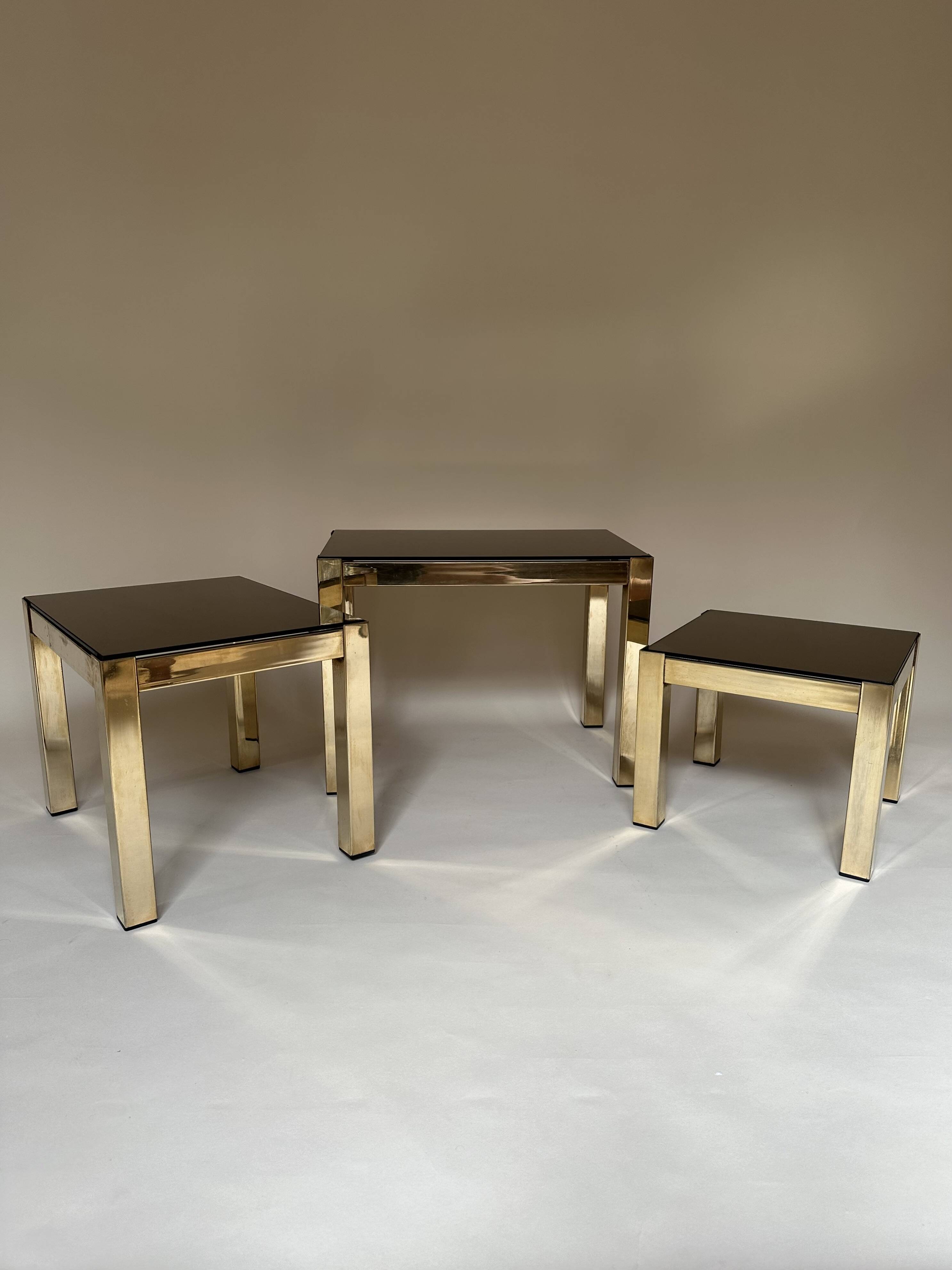 Set of three nesting side tables in brass and smoked mirror.