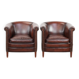 Ensemble de deux fauteuils club en cuir de vachette dans une couleur rouge/marron luxueuse.