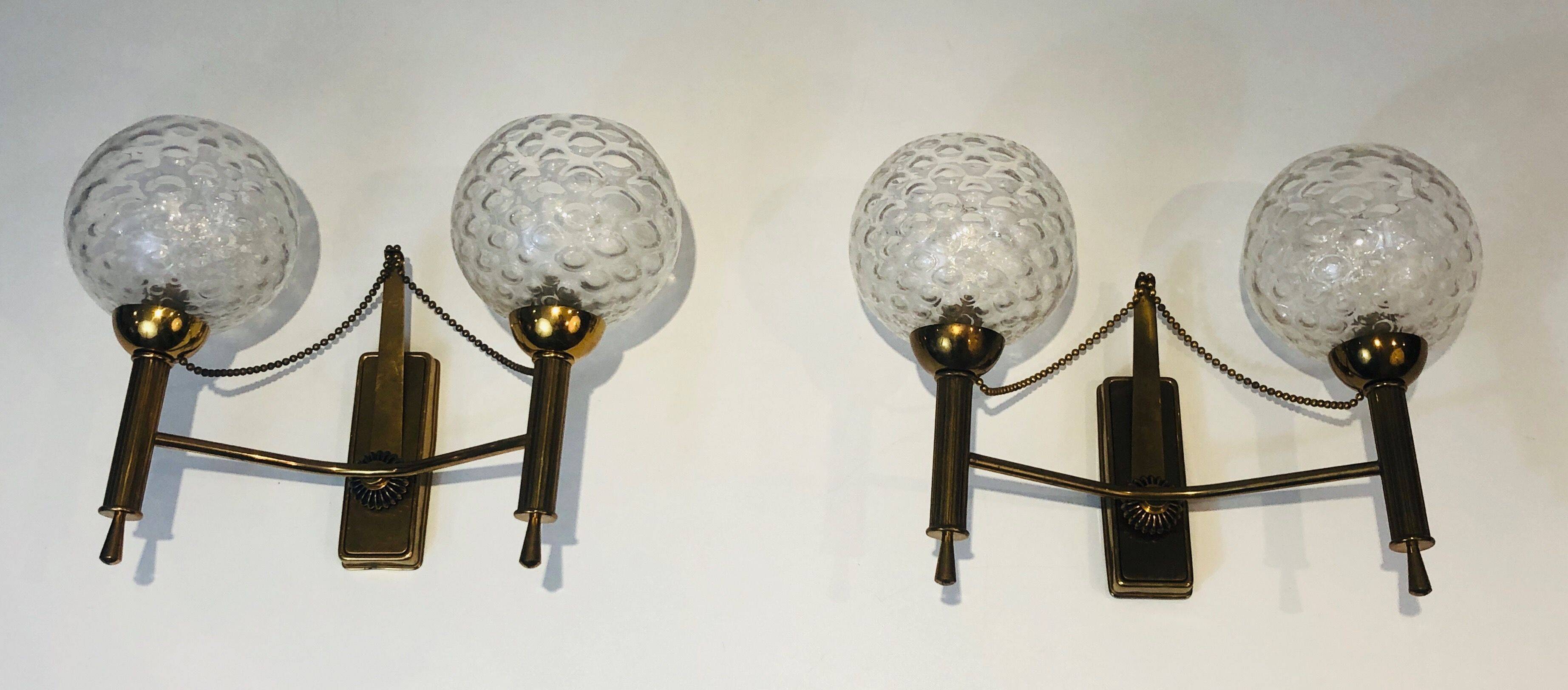 Pair of brass wall lights with glass globes. Around 1970.