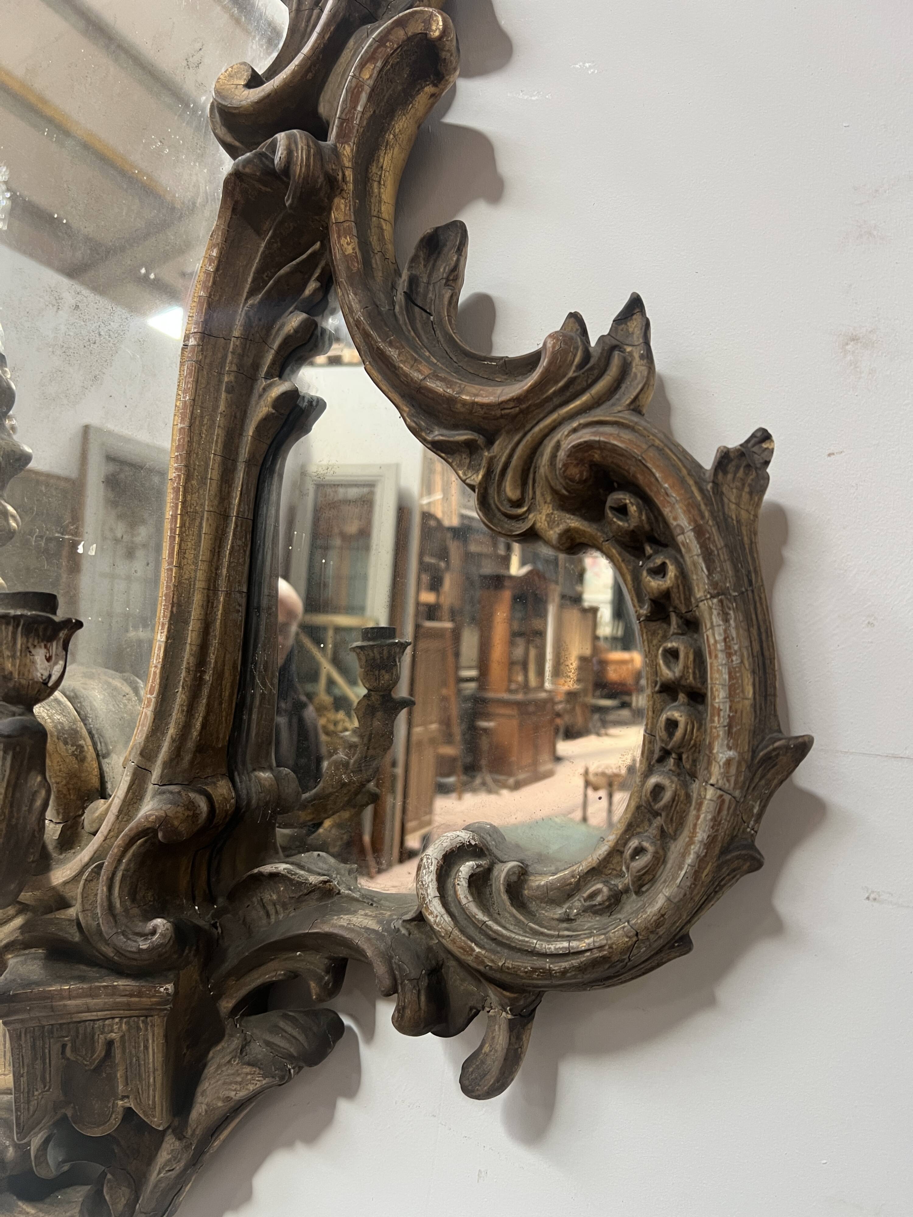 Mirror with a decorative frame featuring a four-light wall sconce, 19th century.