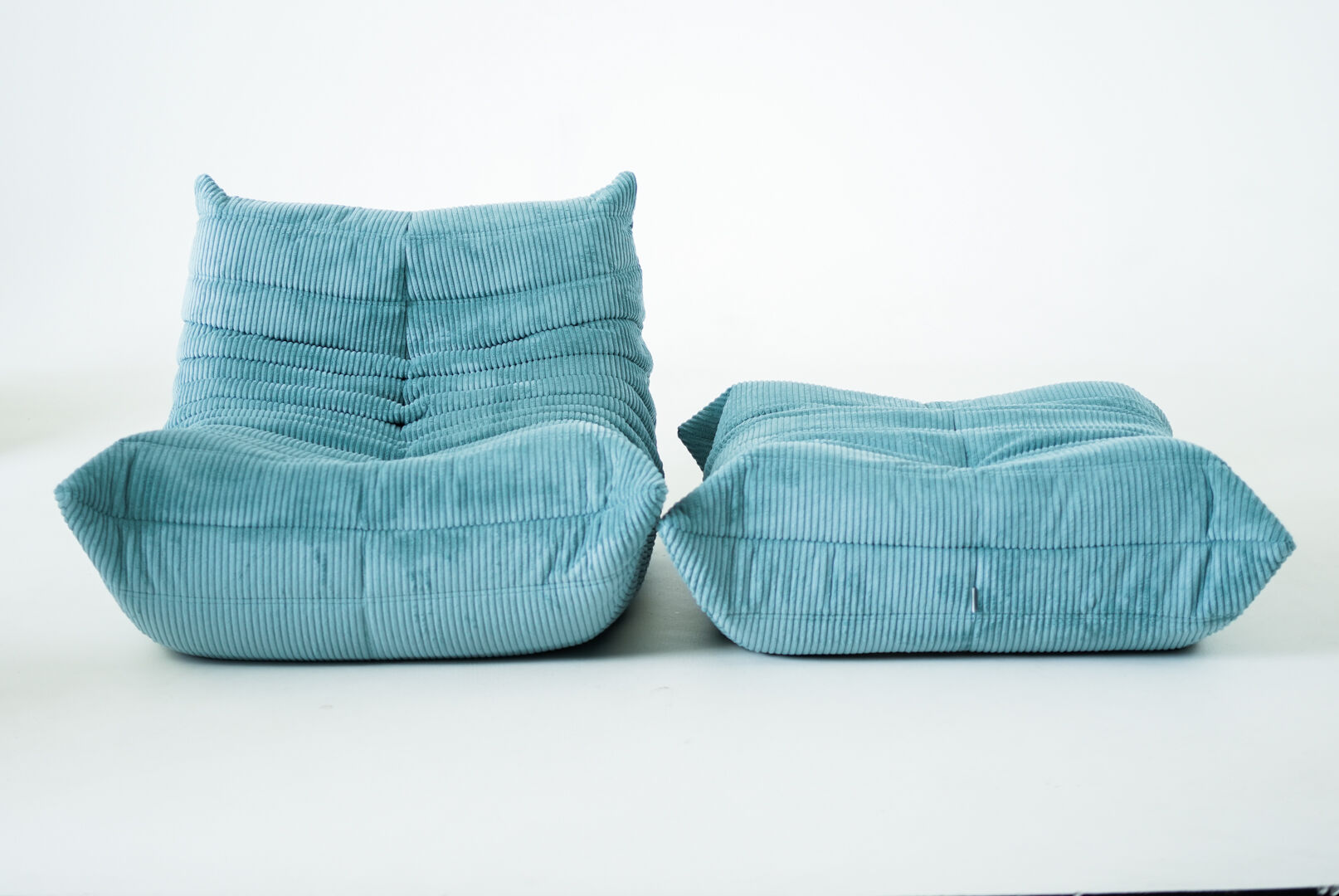Ensemble de fauteuil et pouf Togo en velours côtelé bleu clair.