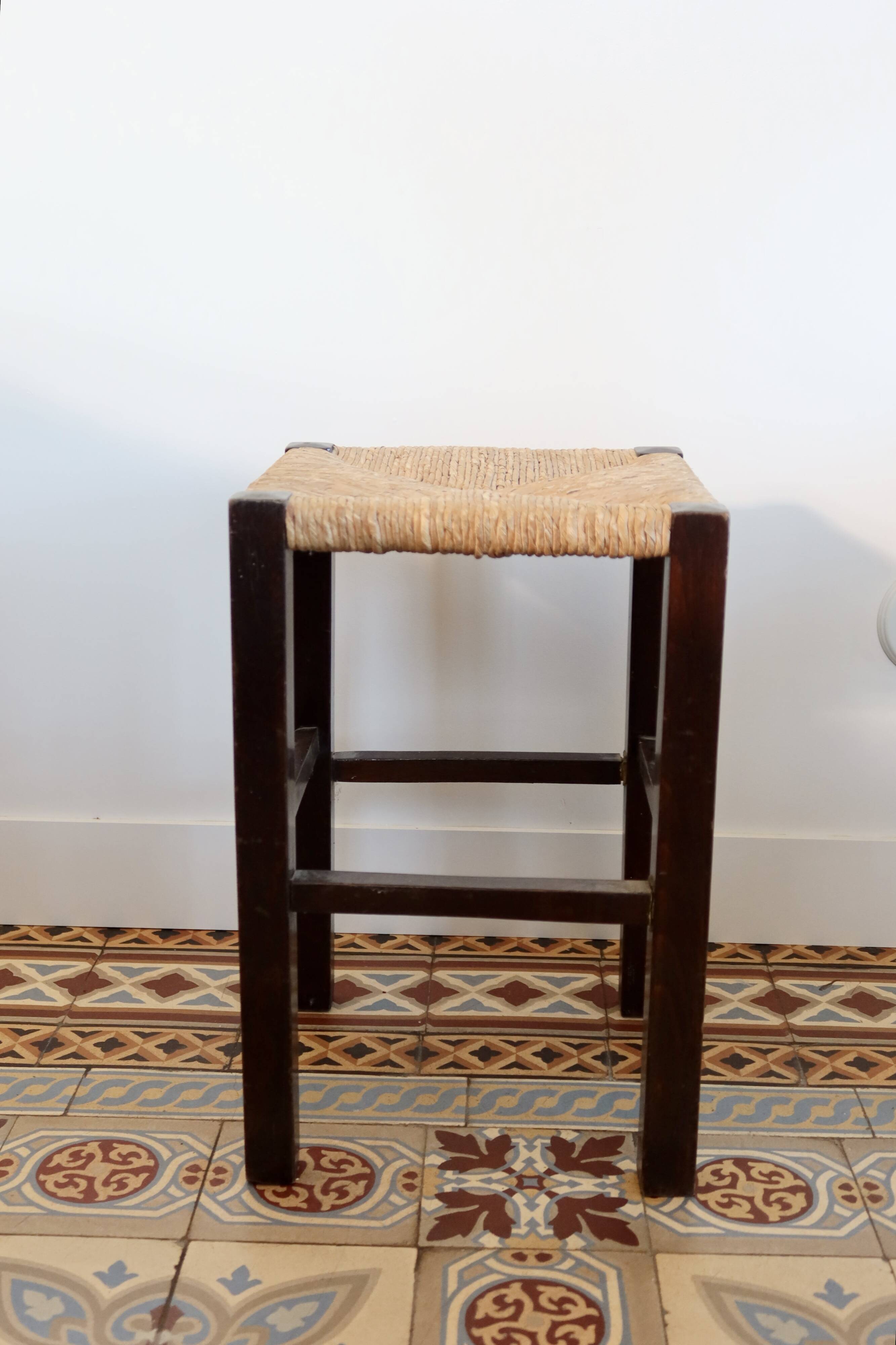 Vintage rustic stool in wood with a straw seat.