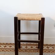 Vintage rustic stool in wood with a straw seat.