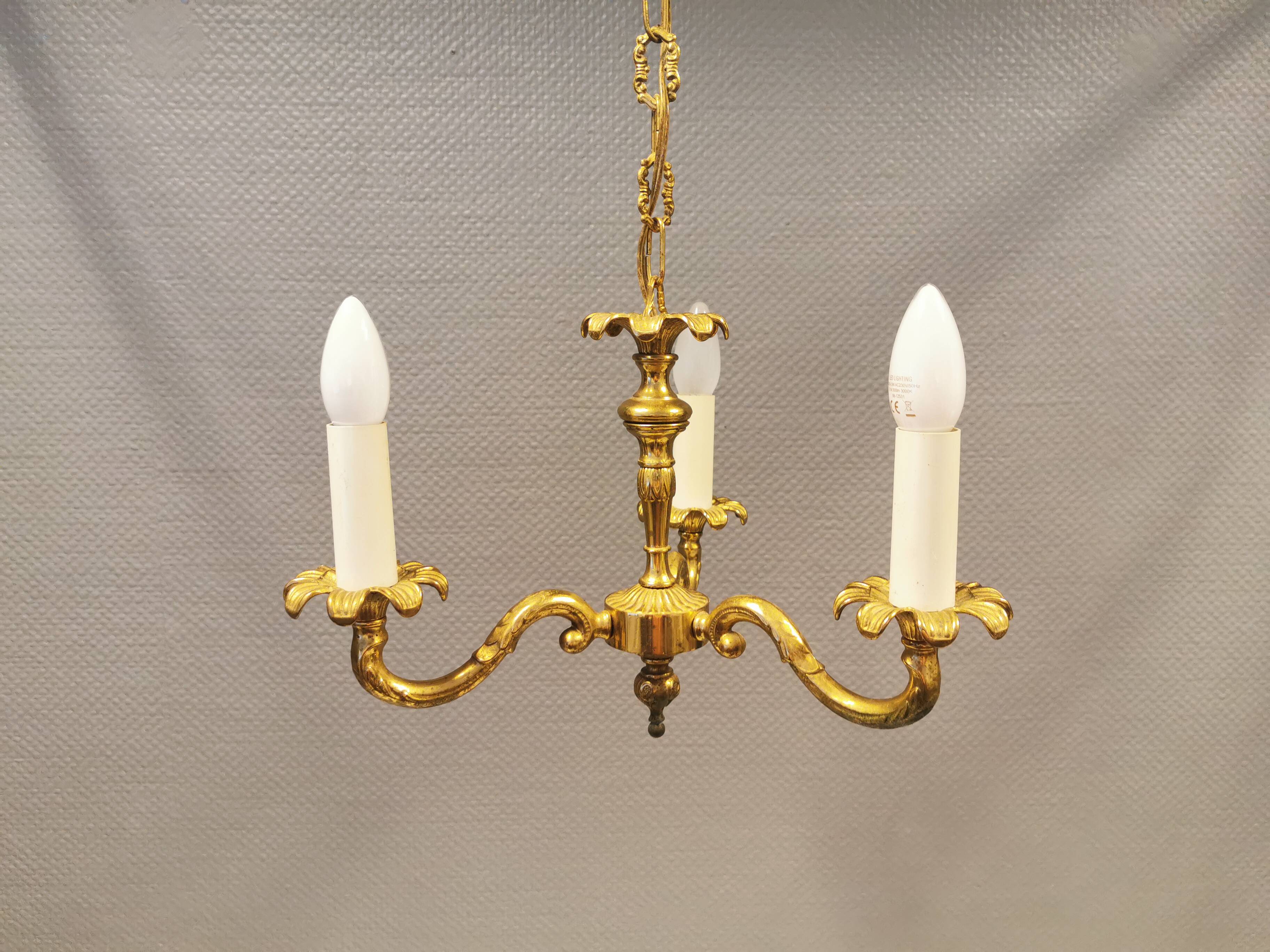 Older brass alloy chandelier with three light sources.