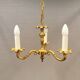 Older brass alloy chandelier with three light sources.