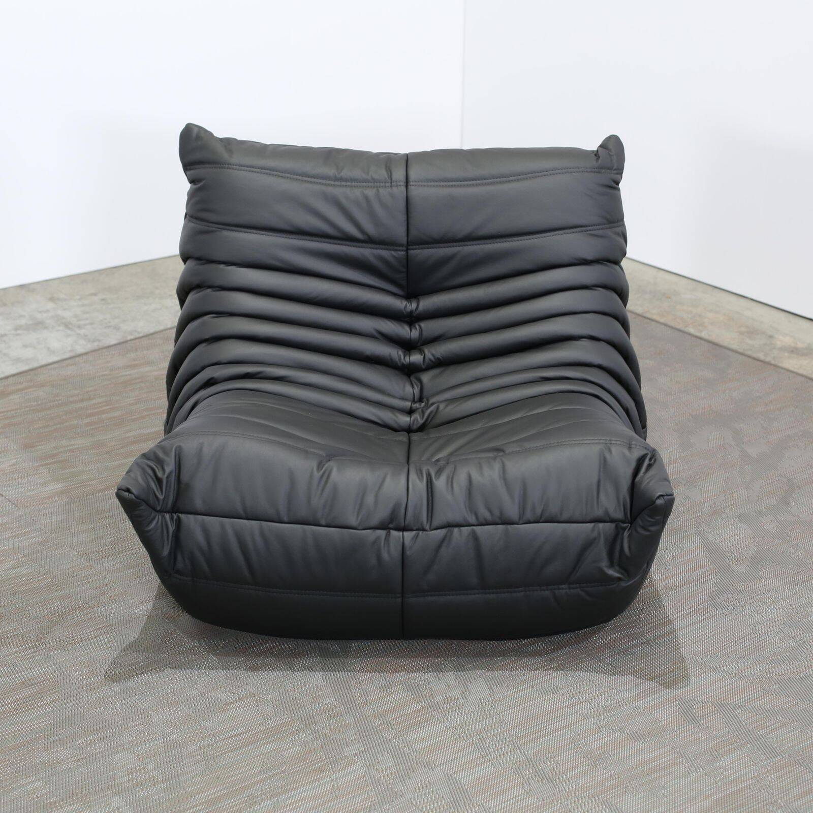Togo armchair and footrest in black leather by Ligne Roset, designed by Michel Ducaroy.