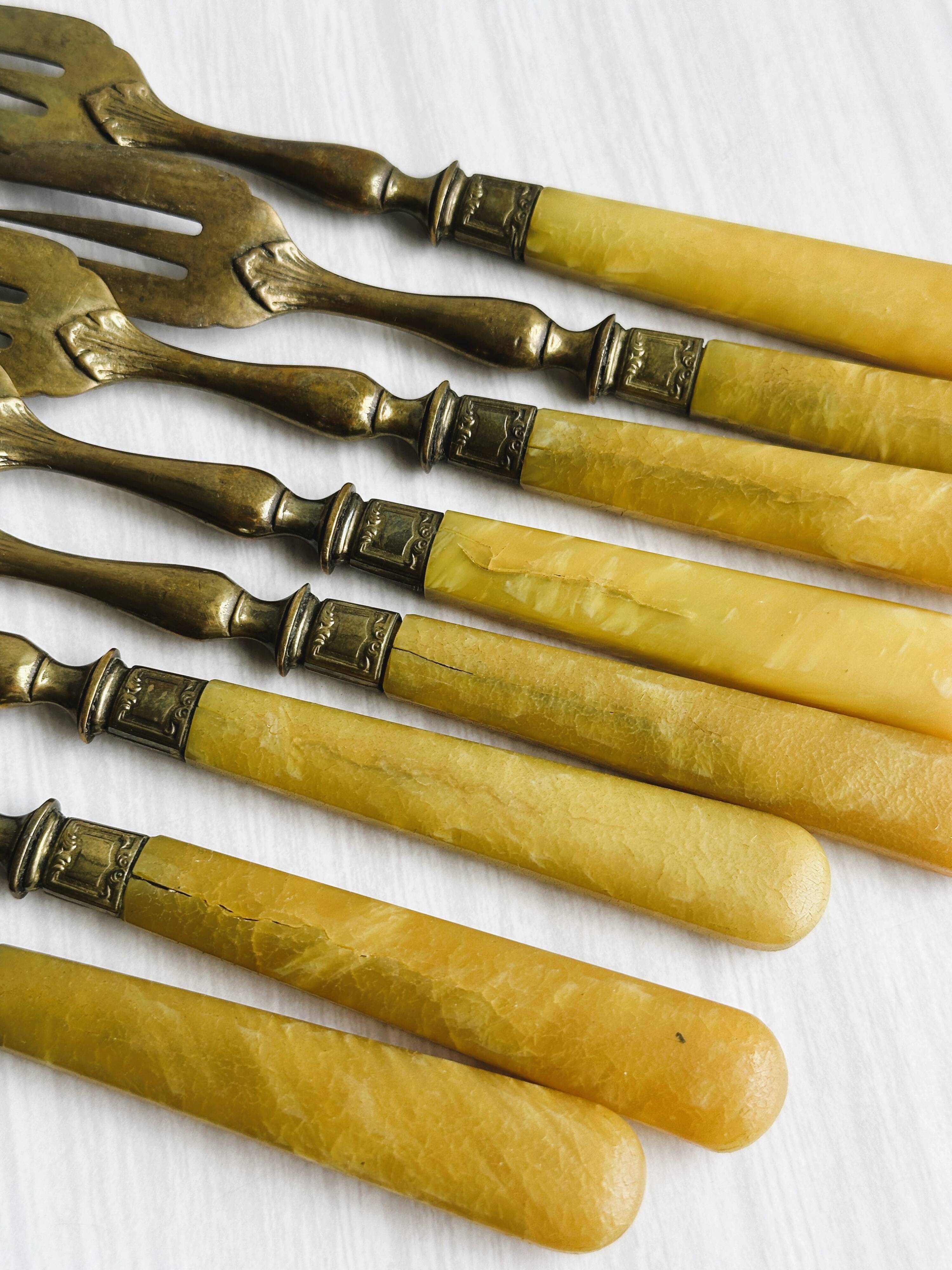 8 fourchettes à dessert vintage en métal doré et  manches en bakélite jaune.