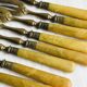8 fourchettes à dessert vintage en métal doré et  manches en bakélite jaune.