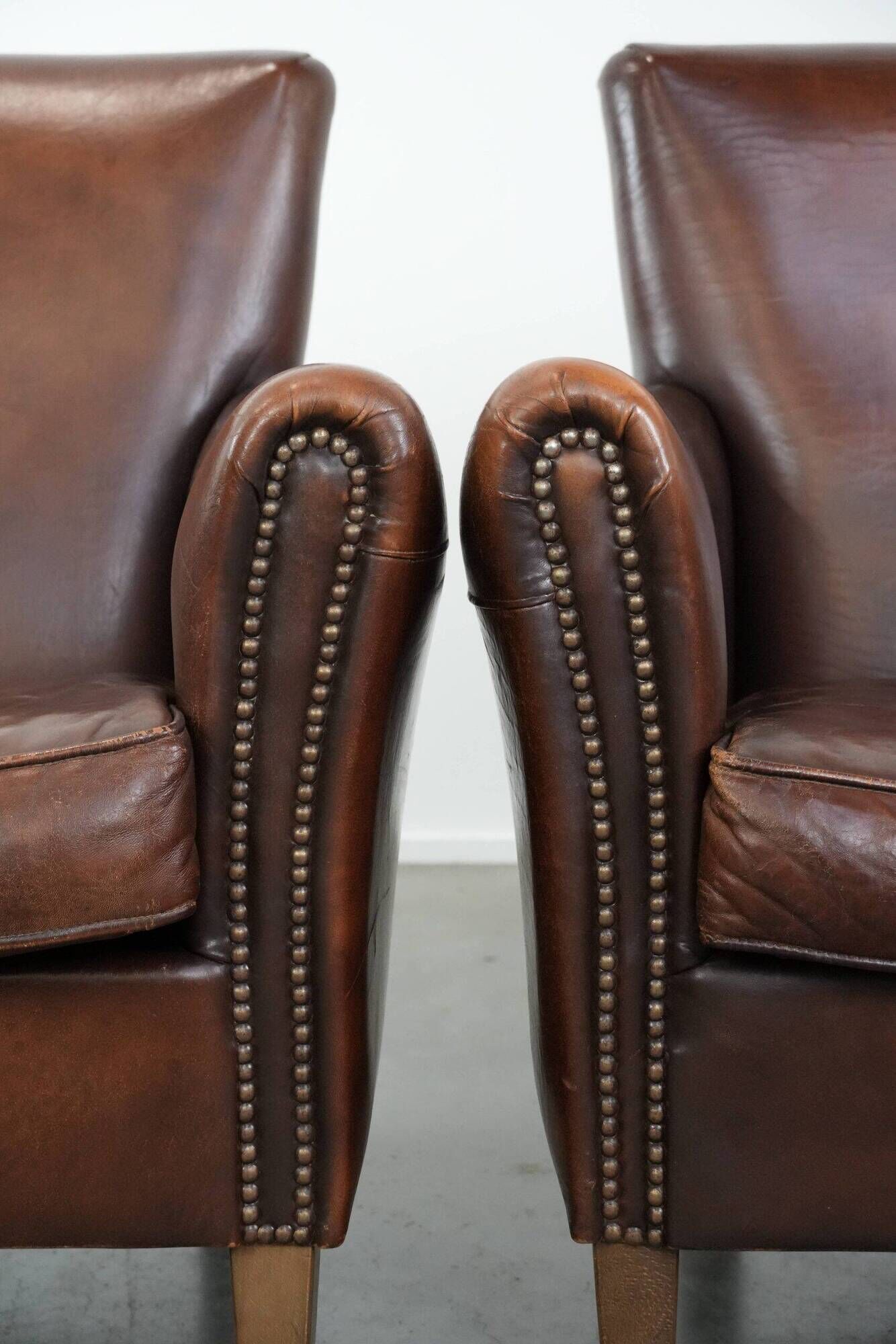 Ensemble de deux fauteuils en cuir de mouton vintage au caractère marqué.
