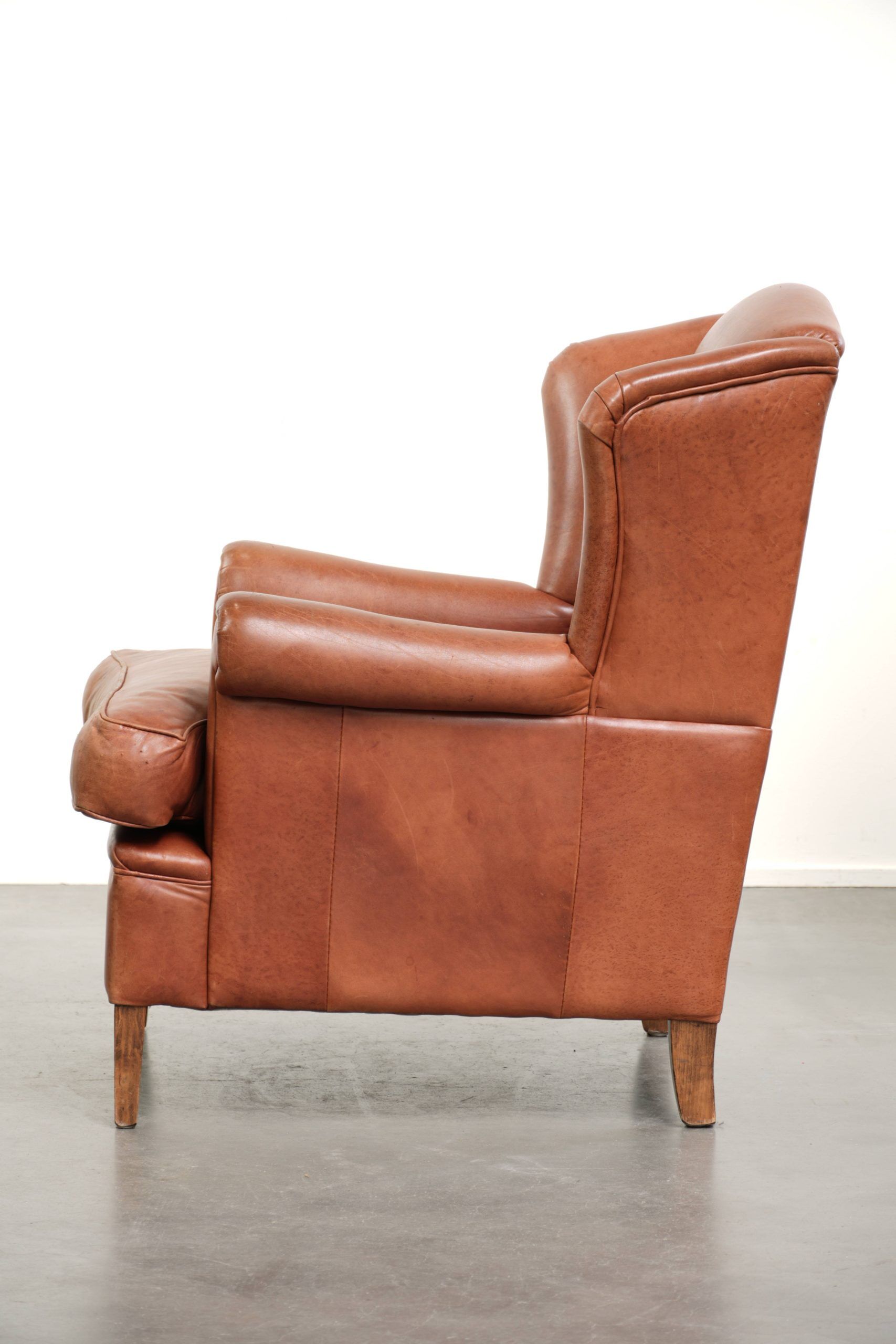 Fauteuil anglais à oreilles de couleur cognac clair en cuir de vache.