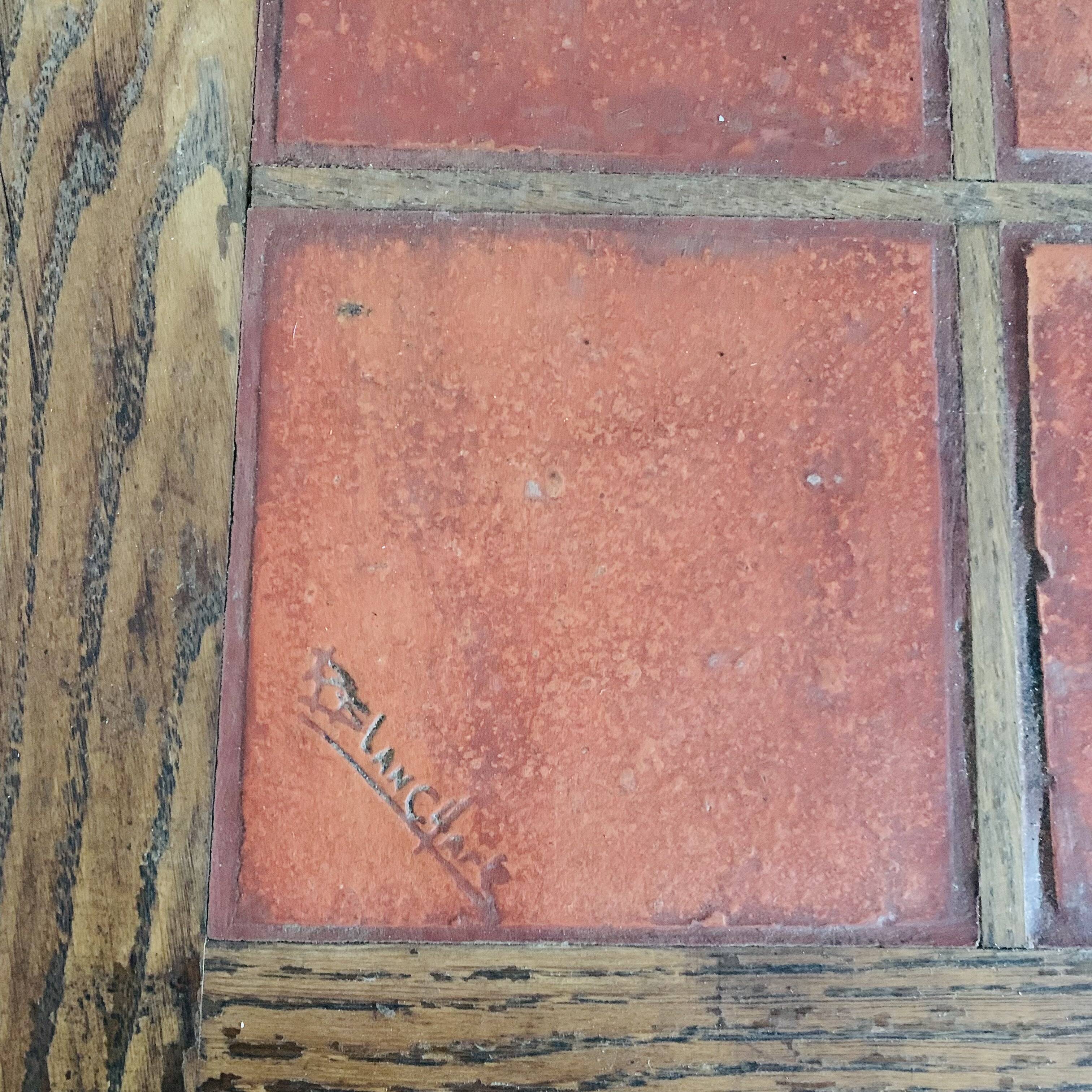 Square table with red tiles signed.