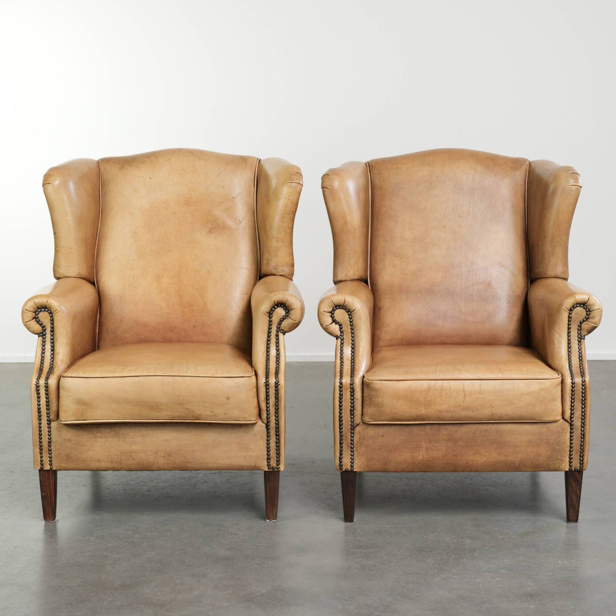 Set of two light cowhide wingback armchairs with a timeless English look