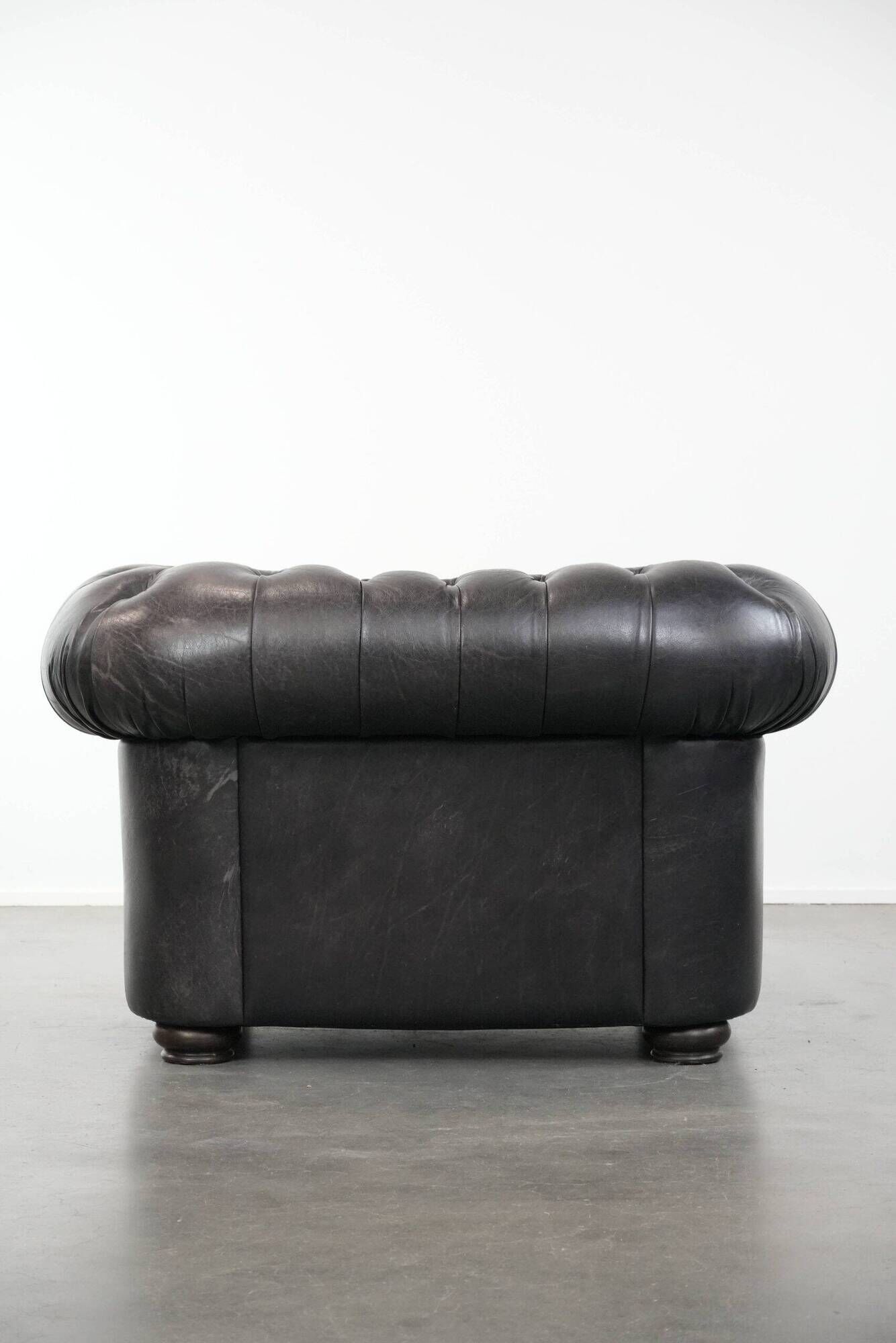 Set of a black cowhide leather Chesterfield armchair and matching ottoman