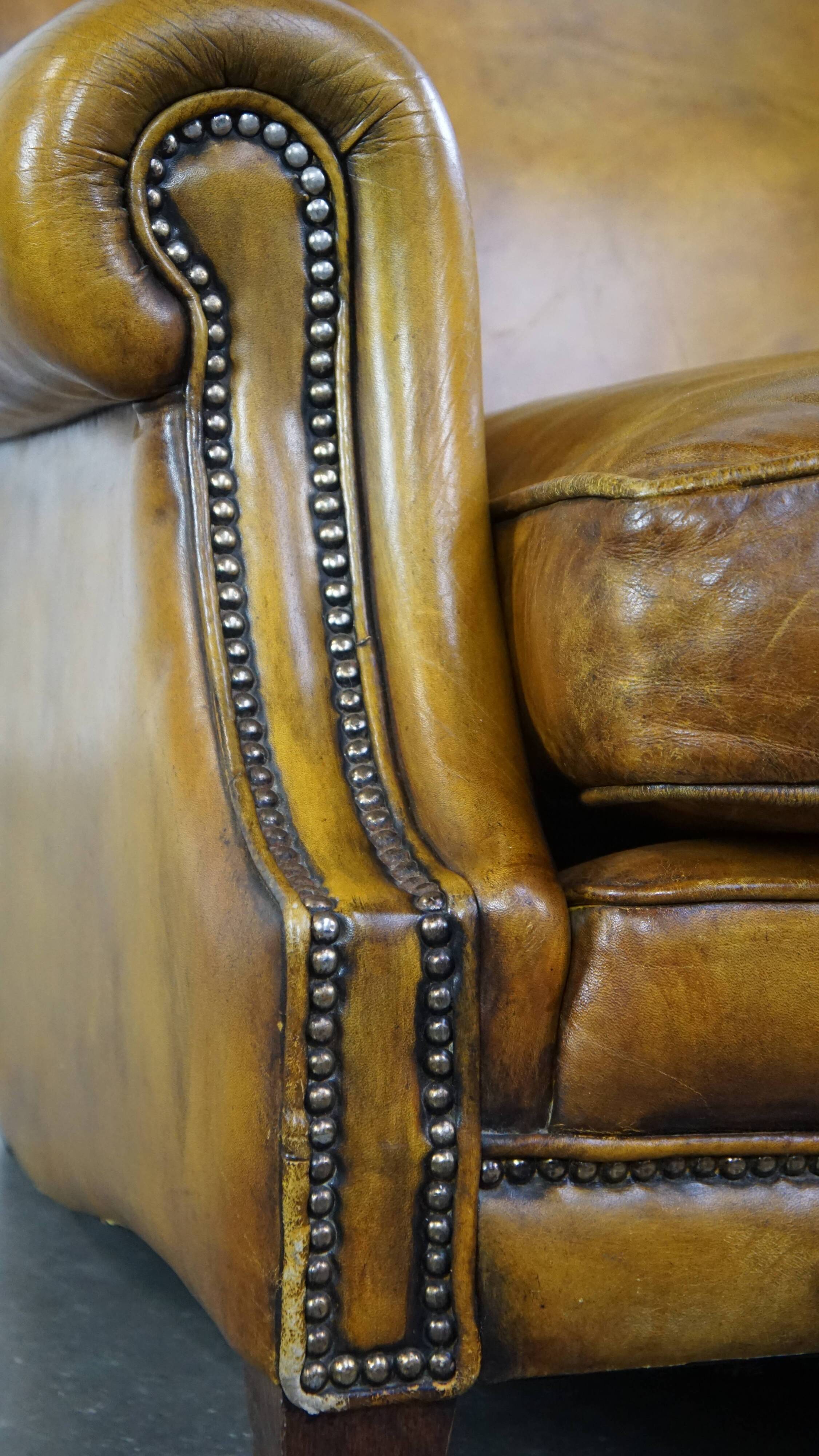 Comfortable large yellow English-style leather armchair with a fine finish and decorative nails