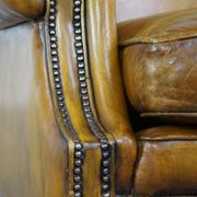 Comfortable large yellow English-style leather armchair with a fine finish and decorative nails