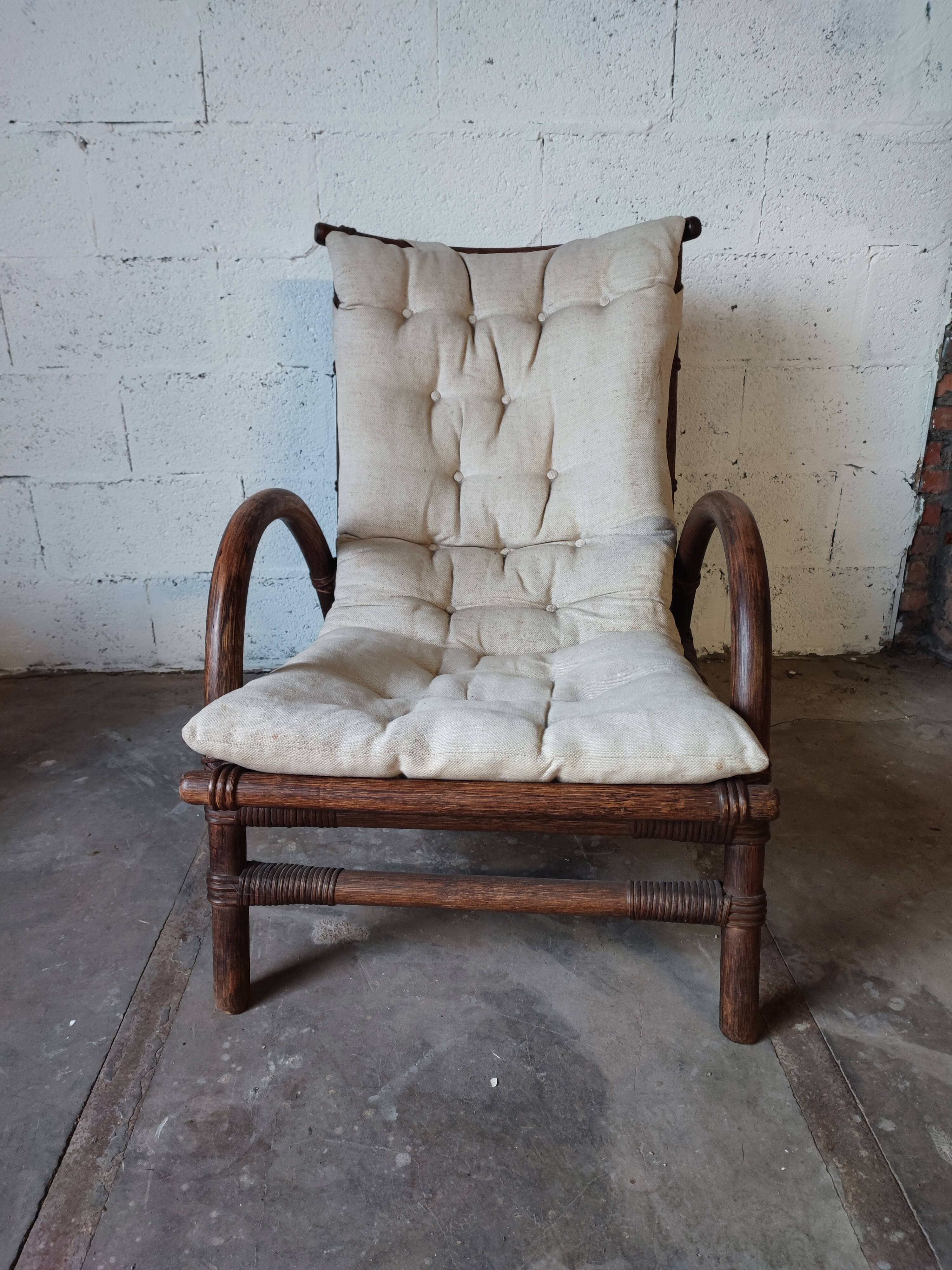 Relaxed armchair in bamboo and rattan with its small side table. Beige linen cushion.