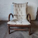 Relaxed armchair in bamboo and rattan with its small side table. Beige linen cushion.