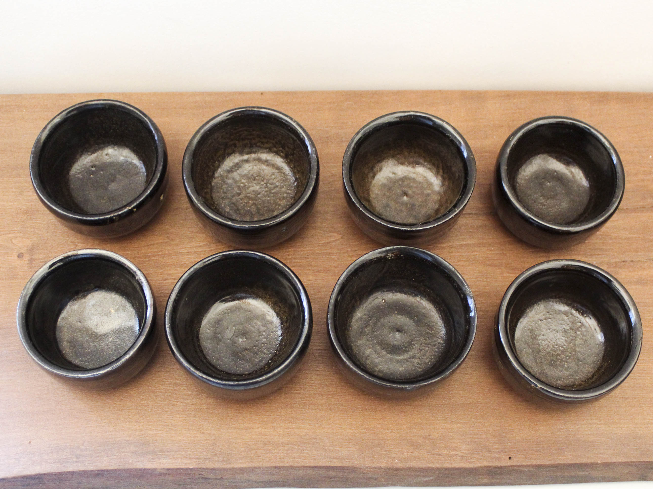 Set of 8 black ceramic cups signed