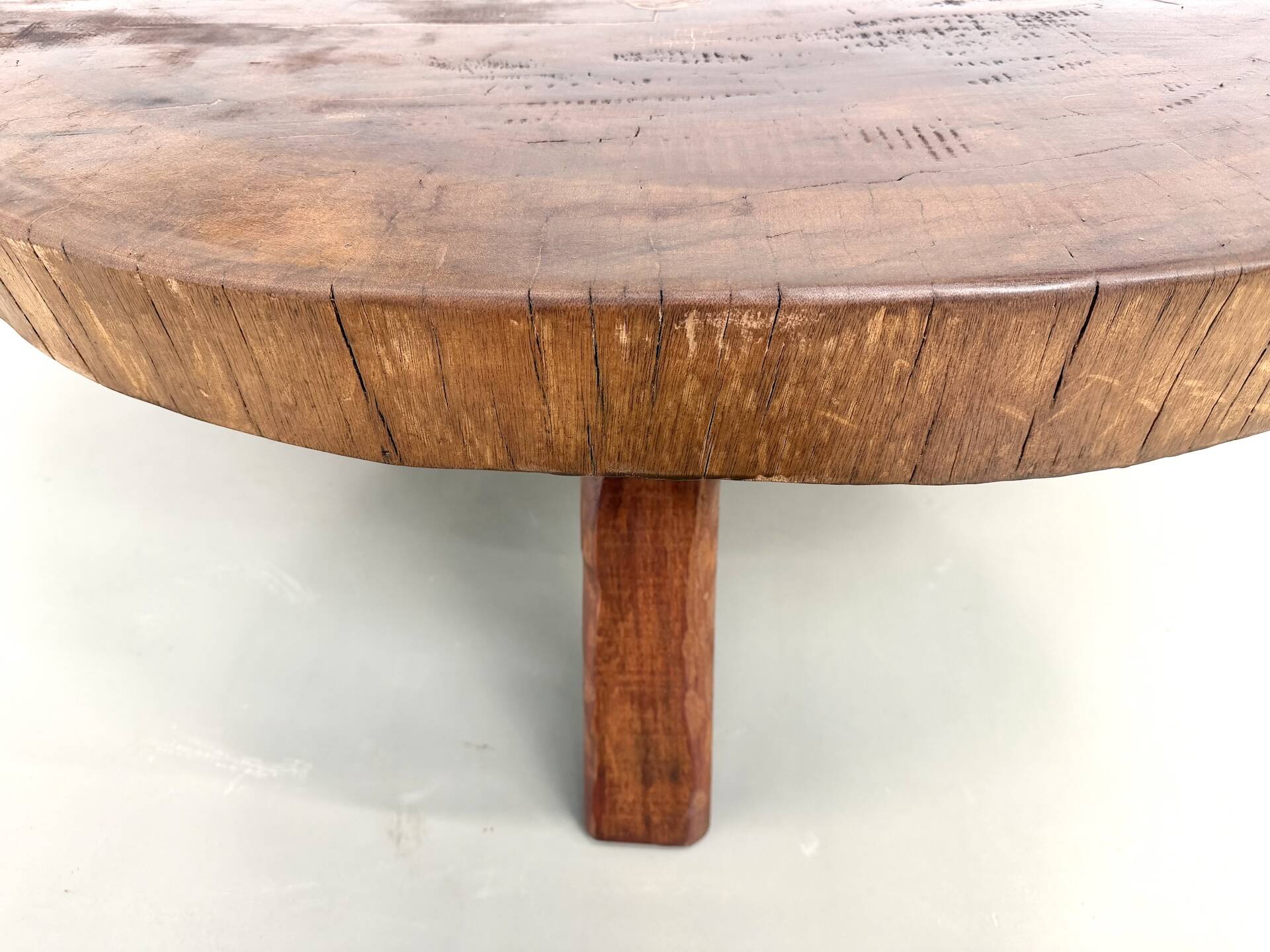 Brutalist coffee table in solid teak, monolithic slab, tripod base.