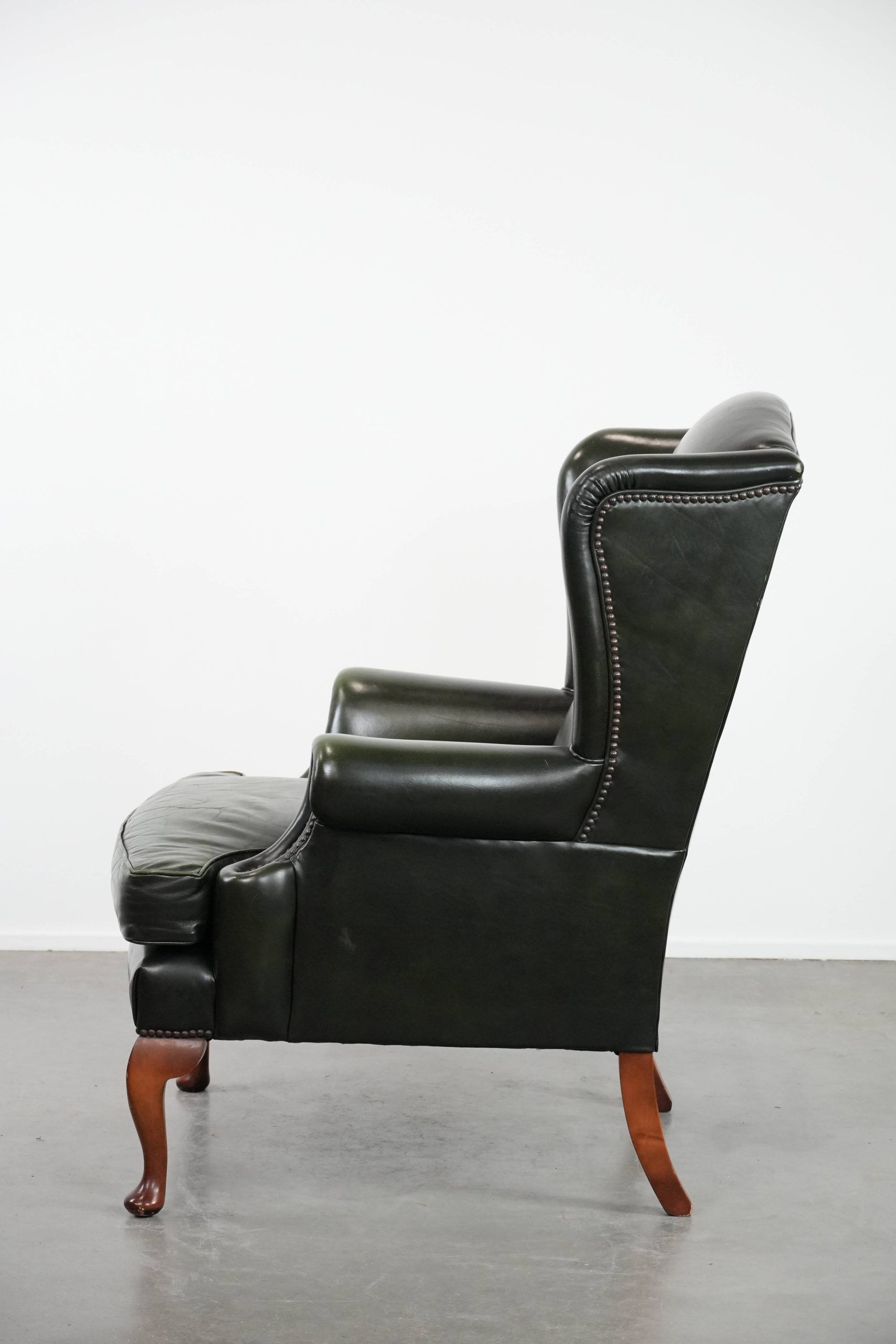 Smooth classic cowhide Chesterfield armchair in a stylish dark green color