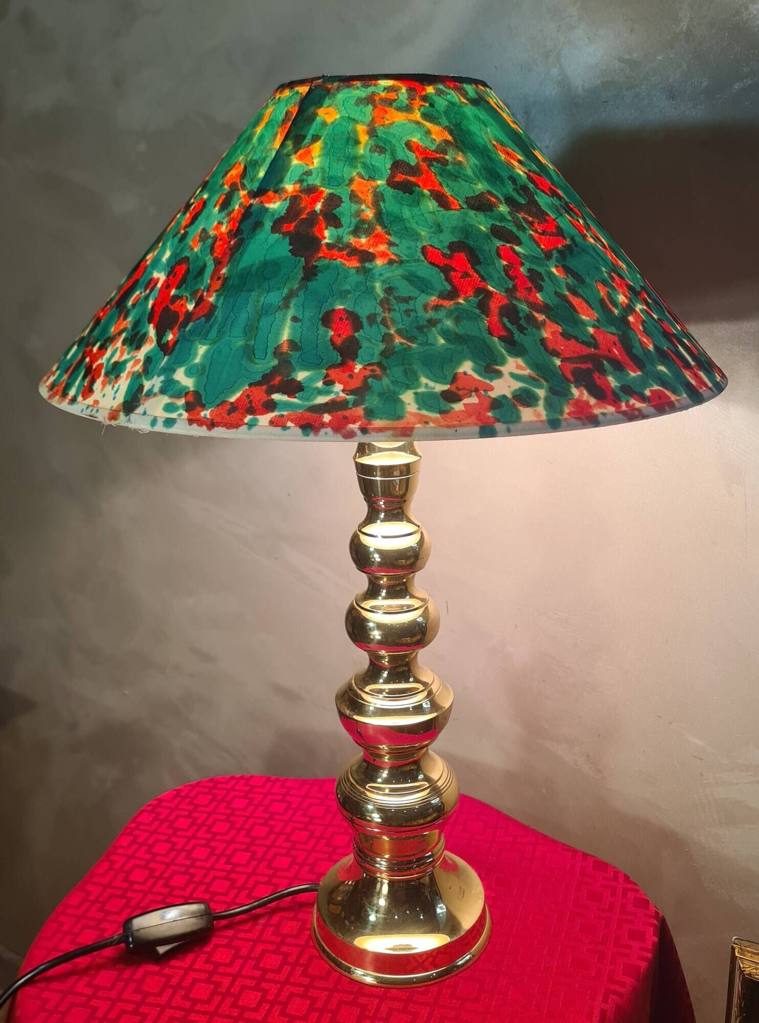 This elegant table lamp features a sculptural base in shiny gold brass.