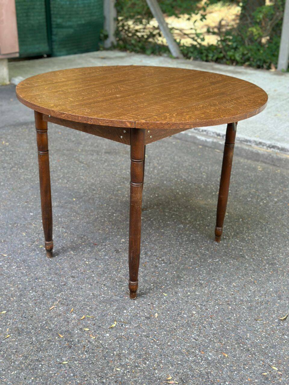 Round kitchen table with extendable leaves in dark wood.