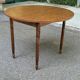 Round kitchen table with extendable leaves in dark wood.