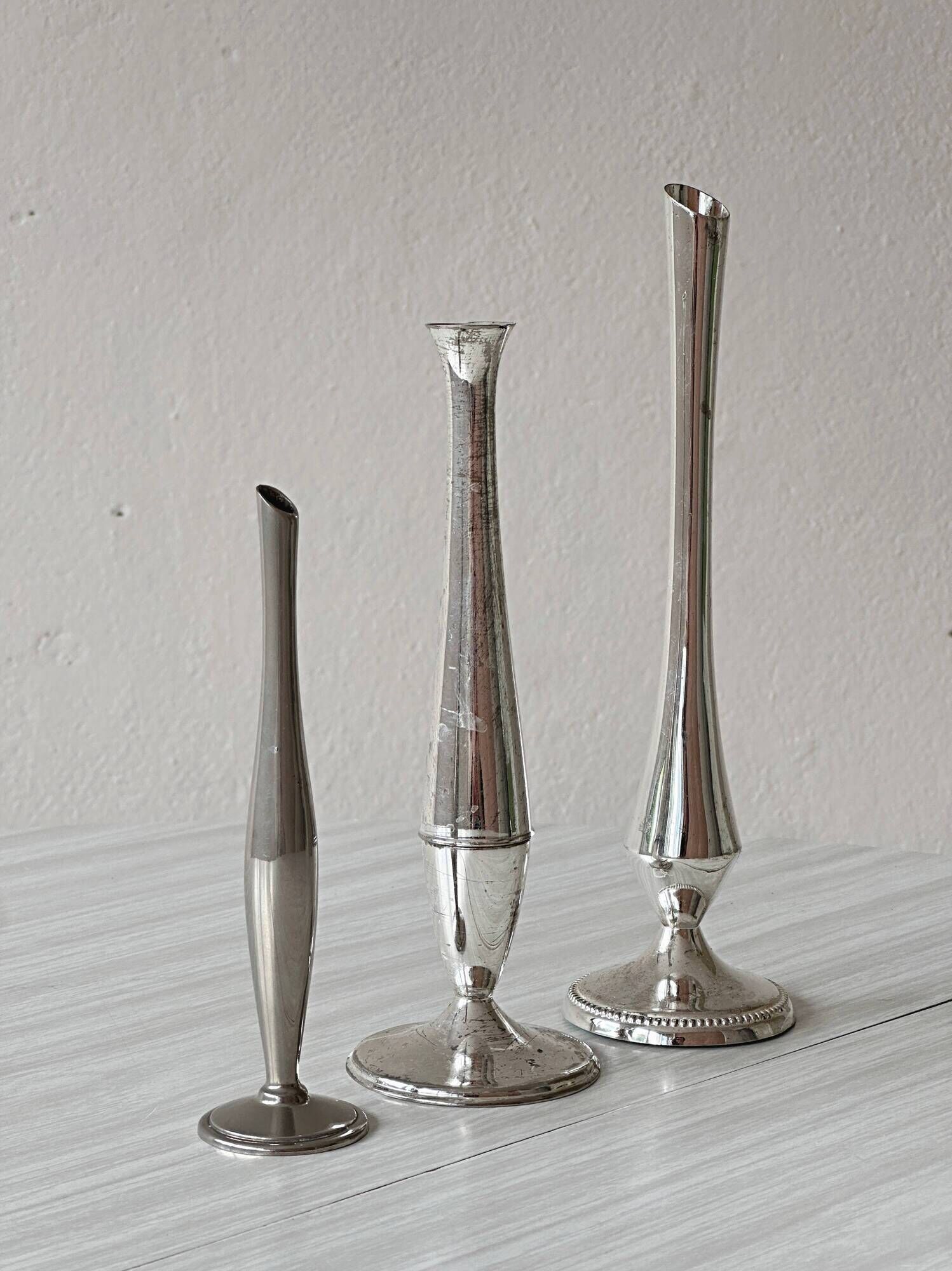 Set of three lightweight silver-coloured metal vases.