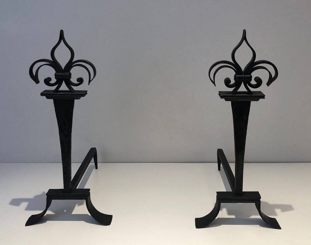 Important pair of wrought iron andirons with torch in heraldic fleur-de-lis design.